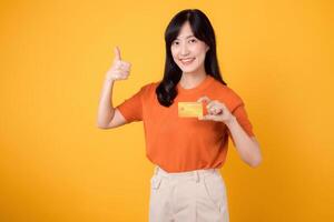 Successful businesswoman in her 30s, holding a credit card and smartphone, making secure online transactions on yellow backdrop. photo