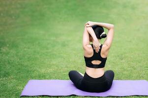retrato ajuste joven 30s asiático mujer en rosado ropa de deporte con yoga estera. extensión músculos en parque. elevar bienestar mediante físico capacitación. deportista abraza el puesta de sol durante su ejercicio. foto