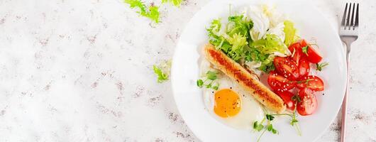 Keto breakfast. Fried egg and chicken sausage and fresh salad. Top view, banner photo