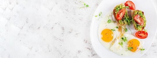Keto breakfast. Fried eggs and toast with guacamole and tomatoes. Top view, banner photo