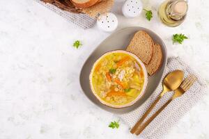 Fresh chicken soup with vegetables and stelline pasta in a bowl with carrot and parsley. Top view, flat lay photo