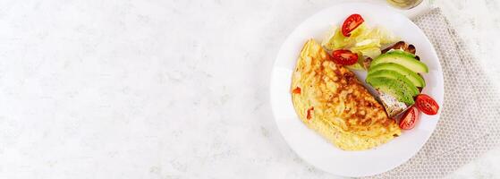 Omelette with tomatoes and toast with avocado on white plate.  Frittata - italian omelet. Top view, banner photo