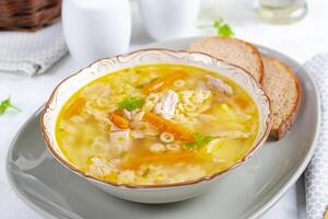 Fresh chicken soup with vegetables and stelline pasta in a bowl with carrot and parsley. photo