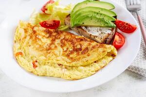 Omelette with tomatoes and toast with avocado on white plate.  Frittata - italian omelet. photo