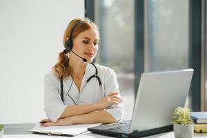 joven hembra médico hablando a paciente en línea desde médico oficina. médico consultante cliente en vídeo charla ordenador portátil a hospital. foto