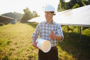 Solar power plant. Man standing near solar panels. Renewable energy. photo