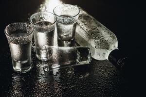 de cerca ver de botella y lentes de vodka en pie aislado en negro. foto