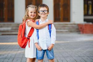 niños Vamos espalda a escuela. comienzo de nuevo colegio año después verano vacaciones. chico y niña con mochila y libros en primero colegio día. foto