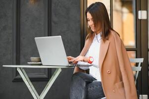 foto retrato de maravilloso atractivo mujer trabajando en ordenador portátil mecanografía sentado en café Bebiendo café