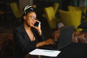 Portrait of a young black woman smiling and using laptop photo