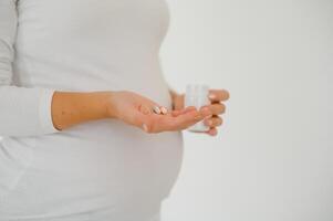 belly of pregnant woman and vitamin pills in the hand photo