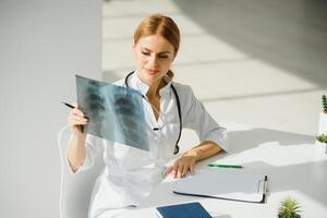 Female doctor working at office desk and smiling, office interior on background. photo