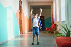 Portrait of a schoolboy standing with a backpack on an empty school hallway. Back to school. photo