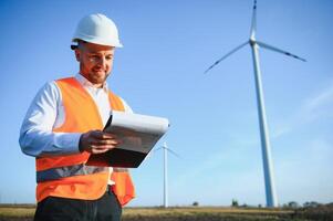 joven ingeniero hombre mirando y comprobación viento turbinas a campo foto