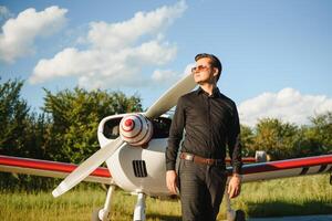 joven hermoso empresario es en pie cerca privado avión. confidente y exitoso hombre en aeropuerto. foto