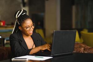 Portrait of a young black woman smiling and using laptop photo