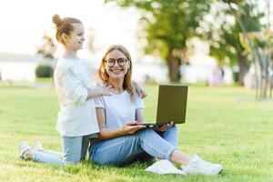 Mom and Daughter with laptop resting on meadow photo