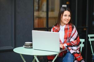 foto retrato de maravilloso atractivo mujer trabajando en ordenador portátil mecanografía sentado en café Bebiendo café