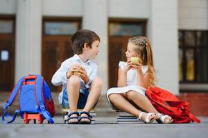 Happy children go back to school. Pupil of primary school go study with backpack outdoors. Kids go hand in hand. Beginning of lessons. First day of fall. Boy and girl from elementary student. photo