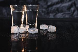 Vodka in shot glasses on dark background photo