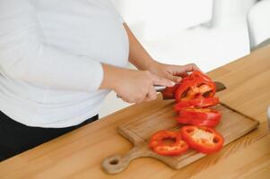 embarazada mujer rebanar vegetales a hogar en el cocina foto