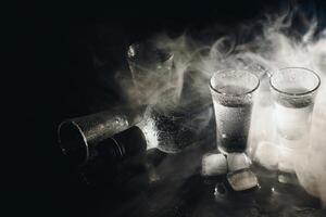 de cerca ver de botella de vodka con lentes en pie en hielo en negro. foto