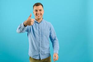 contento sonriente hermoso hombre en ropa, demostración Copiar espacio, visual imaginario o algo, o prensado virtual botón, agua marina azul color antecedentes. foto