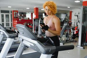 attractive young woman runs on a treadmill, is engaged in fitness sport club photo