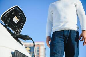 hombre cargos un eléctrico coche a el cargando estación foto