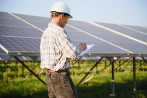 Solar power plant. Man standing near solar panels. Renewable energy. photo