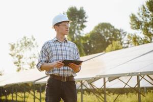 el retrato de un joven ingeniero cheques fotovoltaica solar paneles concepto renovable energía, tecnología, electricidad, servicio, verde fuerza. foto