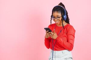 hermosa mujer con afro pelo listado a música y bailando en rosado antecedentes. foto