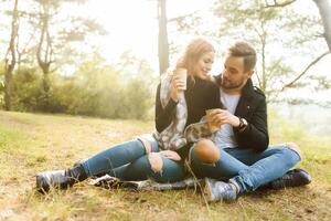 Pareja en amor sentado en otoño caído hojas en un parque, disfrutando un hermosa otoño día foto