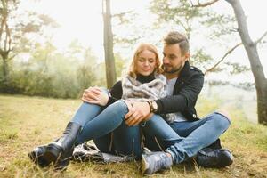 Couple in love sitting on autumn fallen leaves in a park, enjoying a beautiful autumn day photo