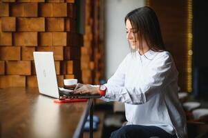 Cute girl freelancer smiling and working with laptop in stylish cafe photo