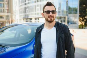 Handsome young man in standing near car outdoors photo