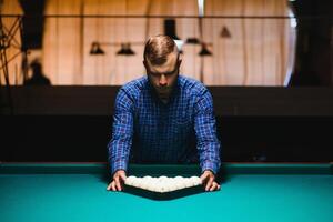 Young man playing billiard. Spending free time on gambling photo