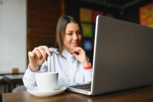 Cute girl freelancer smiling and working with laptop in stylish cafe photo