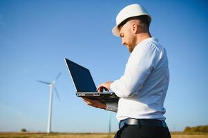 Young engineer man looking and checking wind turbines at field photo