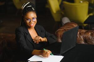 Young African American woman siting at cafe working on laptop photo