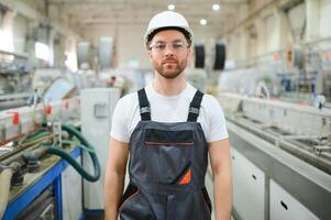 A male worker in a special uniform and an white helmet. Production of frames for PVC windows photo