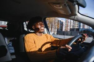 hermoso joven africano americano hombre en su nuevo alta tecnología eléctrico vehículo mientras Bebiendo. yo conducción vehículo concepto foto