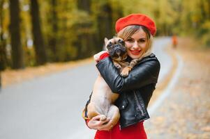 People and dogs outdoors. Beautiful and happy woman enjoying in autumn park walking with her adorable French bulldog. photo