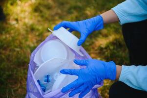 joven hombre recoge basura en un bolsa, trabajar como voluntario foto