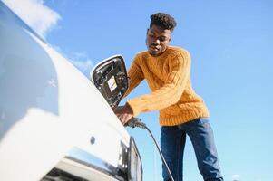 African American man charging his electric car. photo