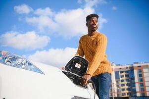 African American man charging his electric car. photo