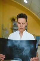 Attractive doctor examining an x-ray and smiling at the camera photo