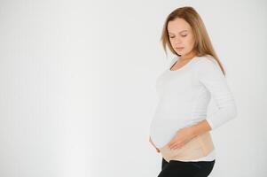 Woman puts on a bandage for pregnant women. Close-up. photo