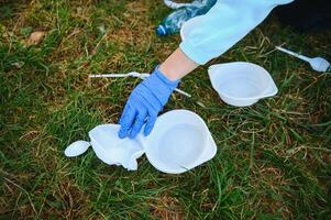 mano pone el plastico escombros en el basura bolso en el parque foto