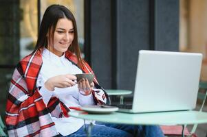 foto retrato de maravilloso atractivo mujer trabajando en ordenador portátil mecanografía sentado en café Bebiendo café